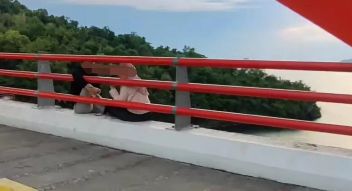 Viral pasangan muda-mudi duduk di tepi Jembatan Merah Jayapura. Warga memberi teguran karena khawatir terjadi kecelakaan di lokasi berbahaya. (Instagram/@eliantiandi)
