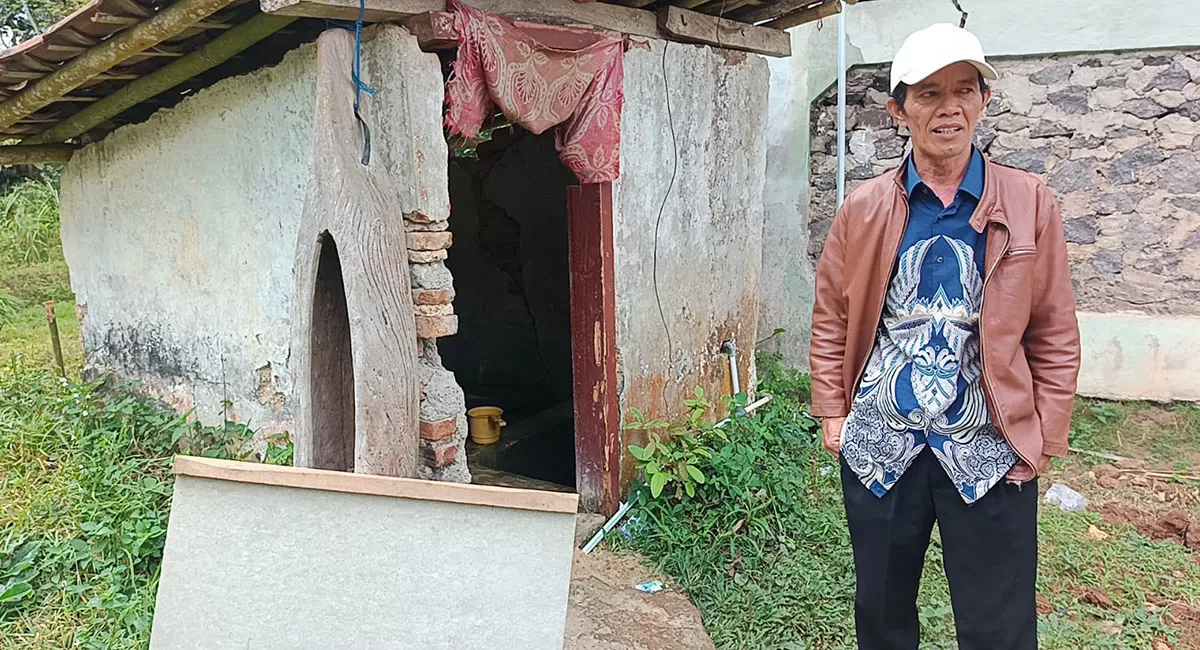 Tokoh masyarakat Kampung Cilintung, Asep Bustopa, menunjukkan kondisi bangunan MCK yang mengalami kerusakan di sejumlah bagian. (Dok. DFK)