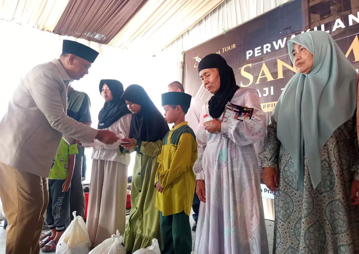 Wakil Bupati Tasikmalaya, H. Asep Sopari Al Ayubi menyerahkan satunan berupa peket sembako dalam acara seremonial pembukaan SANEMA TOUR Haji Umrah dan Wisata Halal di Desa Cikadongdong, Kecamatan Singaparna, Kabupaten Tasikmalaya. (Dok. DFK)