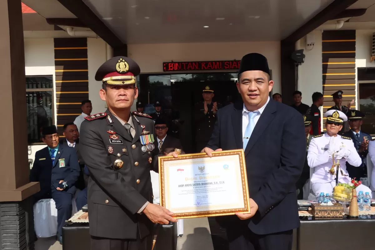 Bupati Bintan, Roby Kurniawan dan Kapolres Bintan, AKBP Argya Satrya Bhawana menunjukkan penghargaan di Upacara Hari Bhayangkara ke-80 di Mapolres Bintan, Rabu 1 Juli 2026.