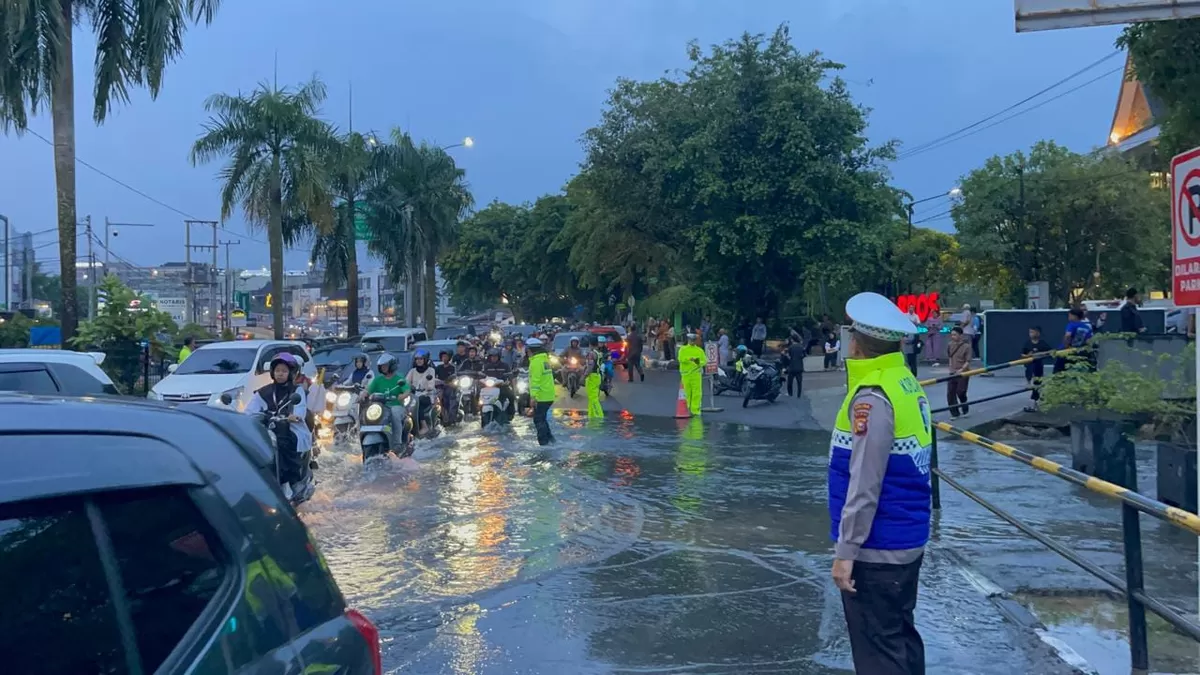 Petugas kepolisian dari Ditlantas Polda Riau dan Satlantas Polresta Pekanbaru memantau arus kendaraan yang melintasi genangan air di Jalan Jenderal Sudirman, Pekanbaru. (Photo Ist.)