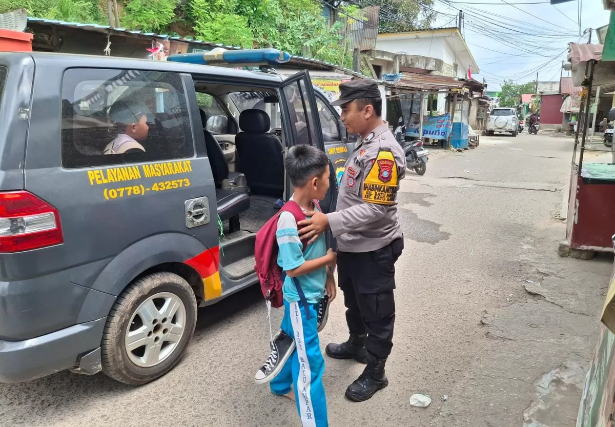 Personel Polsek Batu Ampar Polresta Barelang saat mengantar salah satu siswa hingga ke pintu rumah lewat program inovasi bernama "Antar Murid (Amru). (Humas Polresta Barelang.)