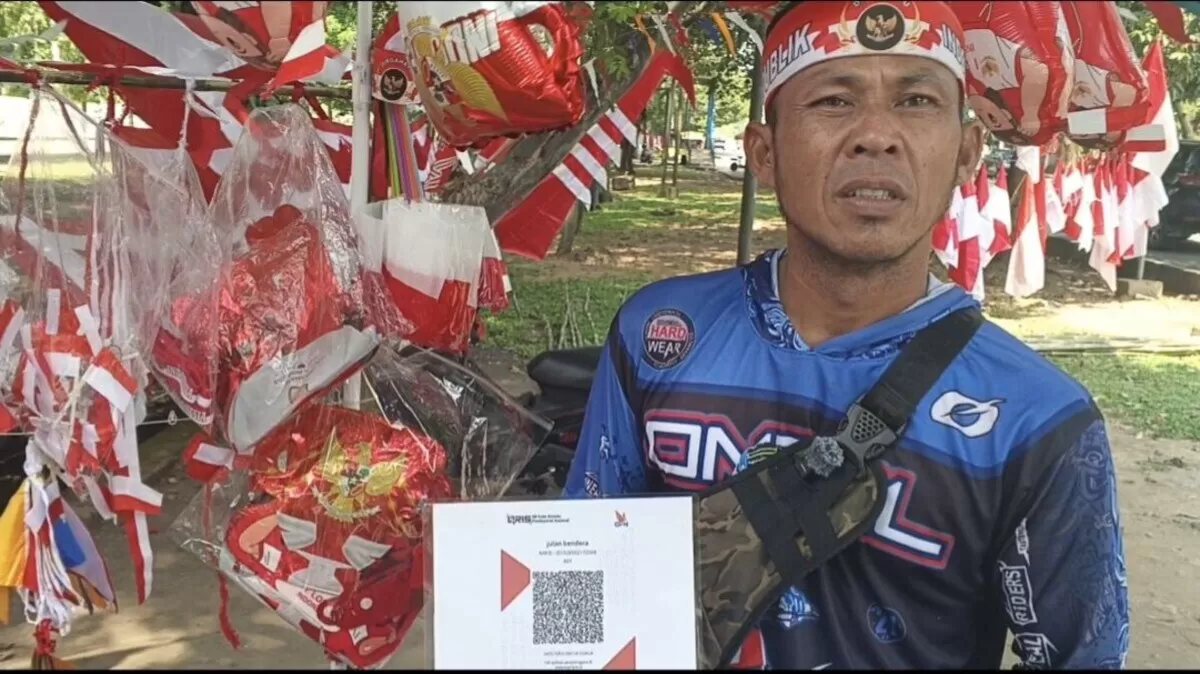 Salah satu penjual bendera Merah Putih, Dani menerapkan pembayaran non tunai QRIS, selain pembayaran tunai.  (Wilhelmus Triputra)