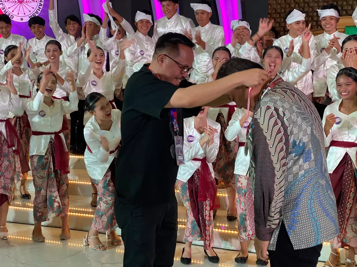 Richard Sualang Mengalungkan Medali Emas ke Coach Wilson Pongoh, mewakili Tim Paduan Suara Remaja GMIM Kalvari Pineleng, 01/08 Malam (Dede/sulutzone.com)