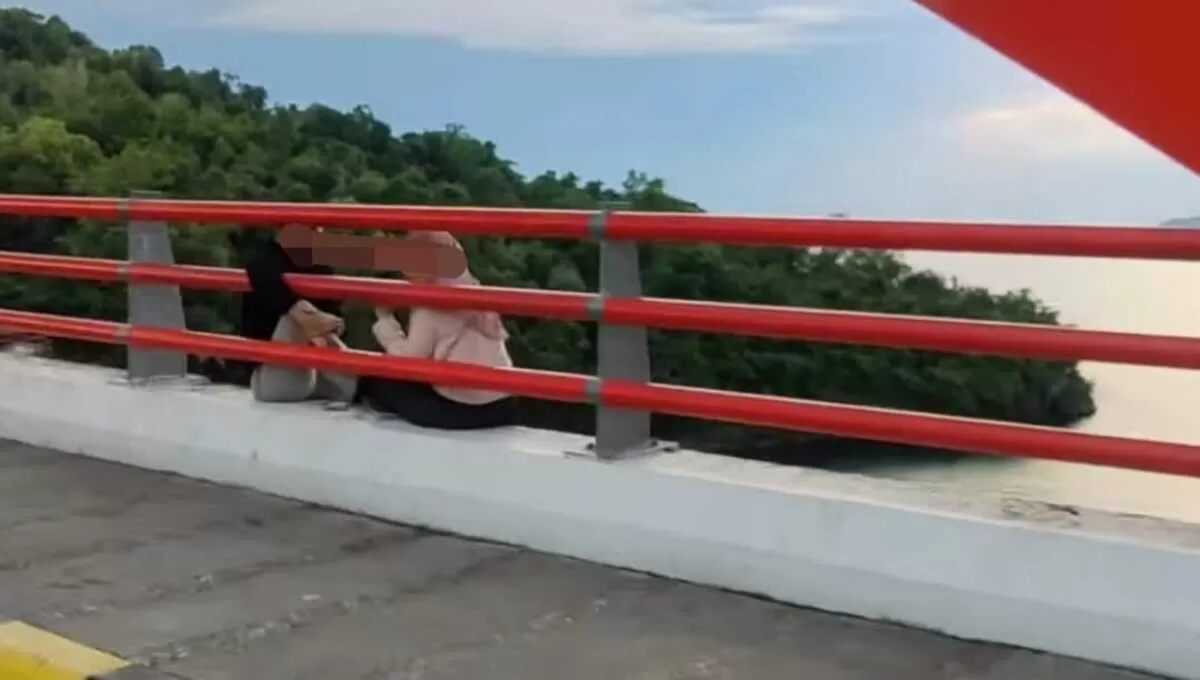 Viral pasangan muda-mudi ditegur warga karena duduk di tepi jembatan di Jayapura, Papua. (Instagram/@eliantiandi)