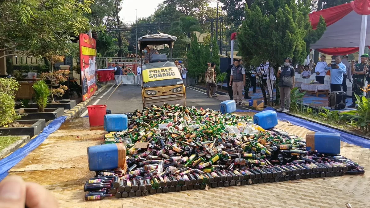 Alat berat jenis road roller menggilas ribuan botol minuman keras hasil Operasi Pekat yang dimusnahkan Polres Subang untuk menjaga kamtibmas jelang Lebaran, Rabu 11 Maret 2026