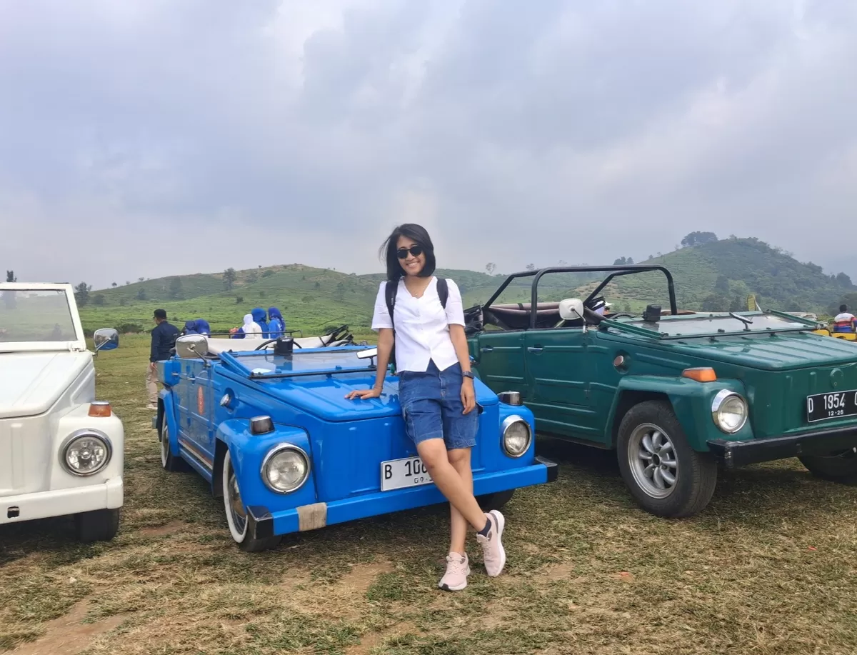 Dini, wisatawan asal Cijantung, Jakarta, berpose di samping mobil klasik Volkswagen (VW) saat menikmati wisata alam di kawasan Ciater, Subang, Minggu, 19 Juli 2026