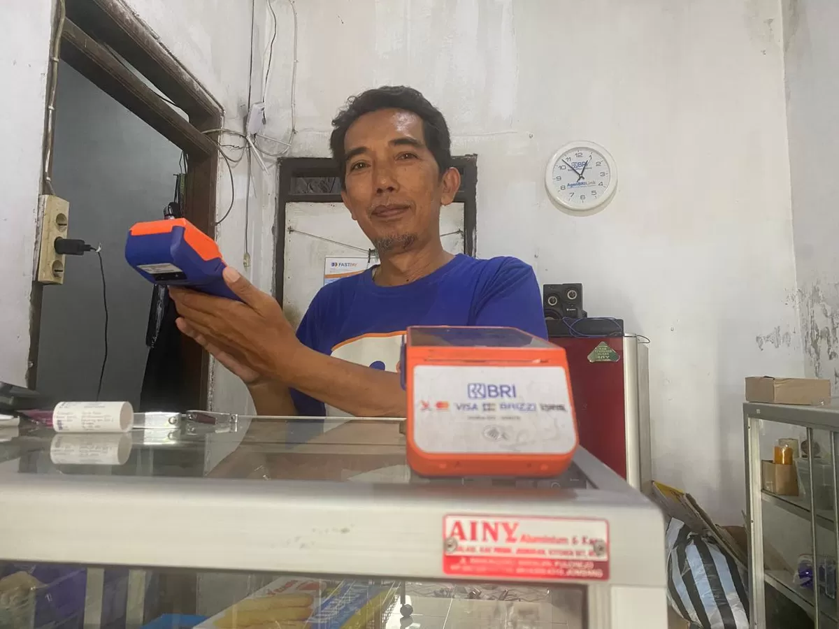 Mochamad Effendi menunjukkan EDC (Electronic Data Capture ) dari Bank BRI yang digunakannya untuk pelayanan transaksi pembayaran non tunai melalui BRILink yang ia kelola. (SketsaNusantara.id/As ad Choirudin)