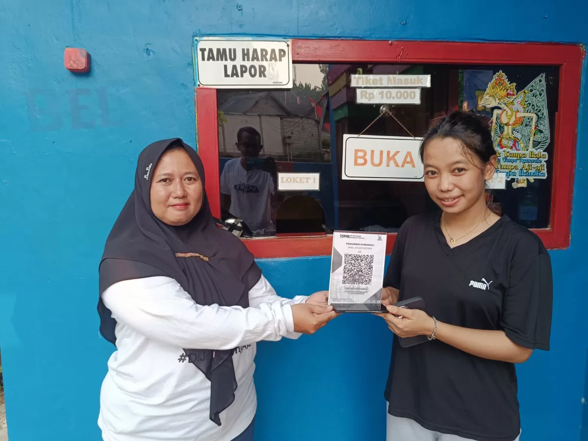 Kepala Unit Wisata Kolam Renang Pandan Sili, Murniasih Dwi Rahayu (kiri) bersama penjaga loket menunjukkan merchan QRIS. (SketsaNusantara.id/As'ad Choirudin)