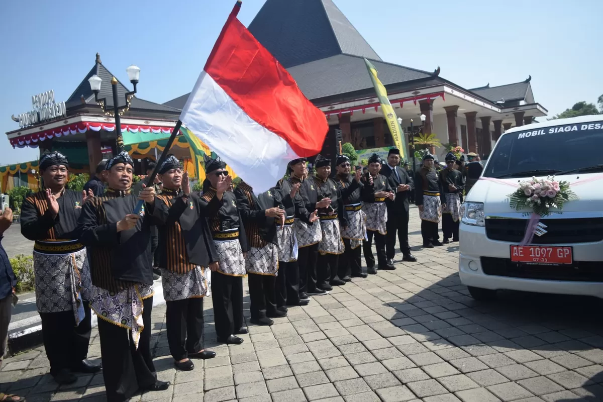 Bupati Madiun Hari Wuryanto (mengibarkan bendera) melepas 55 unit mobil siaga desa secara simbolis. (SketsaNusantara.id)