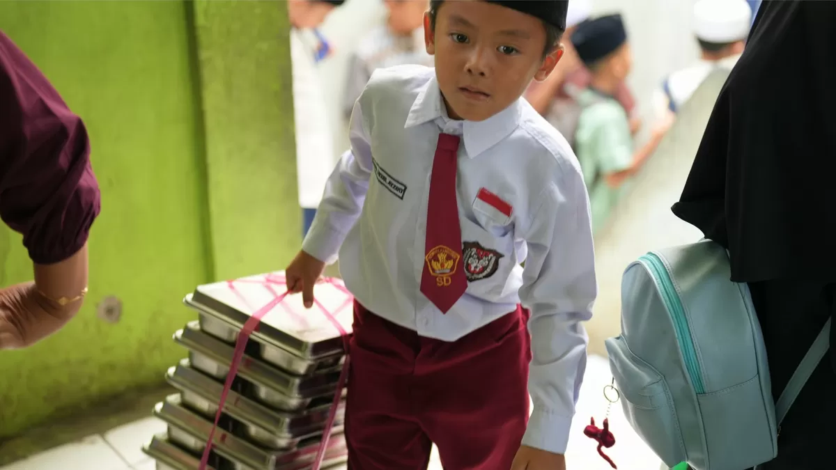 Siswa membawa tumpukan nampan dari SPPG. (dok. Biro Hukum dan Humas BGN)