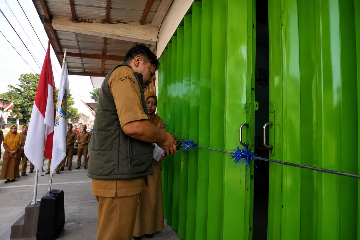 Kepala SMKN 3 Bondowoso Daris Wibisono Setiawan sedang memotong rantai untuk meresmikan bengkel sepeda motor. (As'ad Choirudin/SketsaNusantara.id)