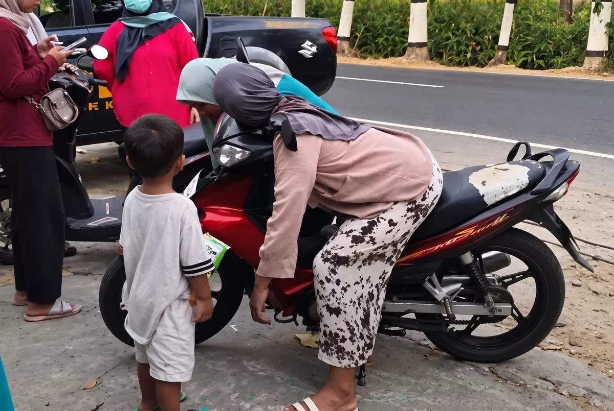 Petugas kepolisian berada di lokasi saat Lu'luatun Nikmah ditemukan meninggal di atas sepeda motor, sementara anaknya berada di dekat motor. (Ist)