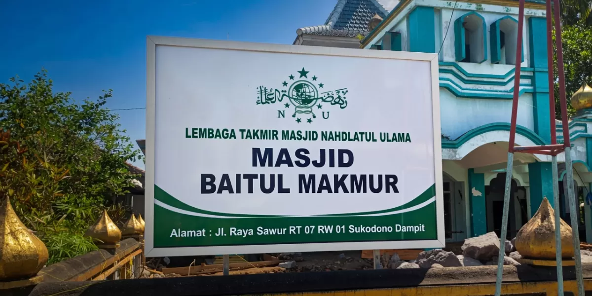 Papan nama Masjid Baitul Makmur Sukodono, lokasi renovasi dan pengembangan rumah ibadah di Dusun Sawur, Desa Sukodono, Kecamatan Dampit, Kabupaten Malang.
