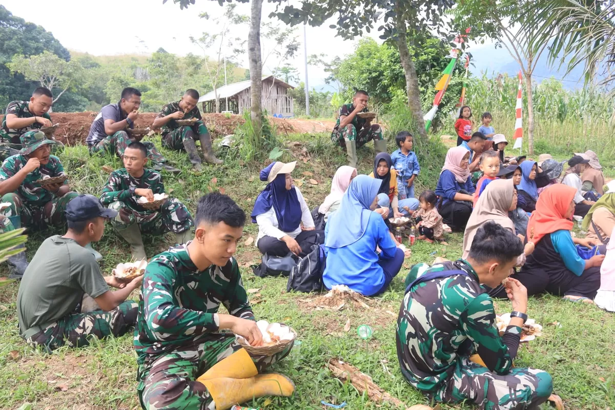 Warga terlihat bekerja berdampingan dengan anggota TNI. Setelah lelah mengangkut material dan meratakan jalan, mereka beristirahat sambil menikmati makan siang sederhana bersama. (Dokumentasi  kegiatan TMMD ke-128 Kodim 0611/Garut, 2026.)