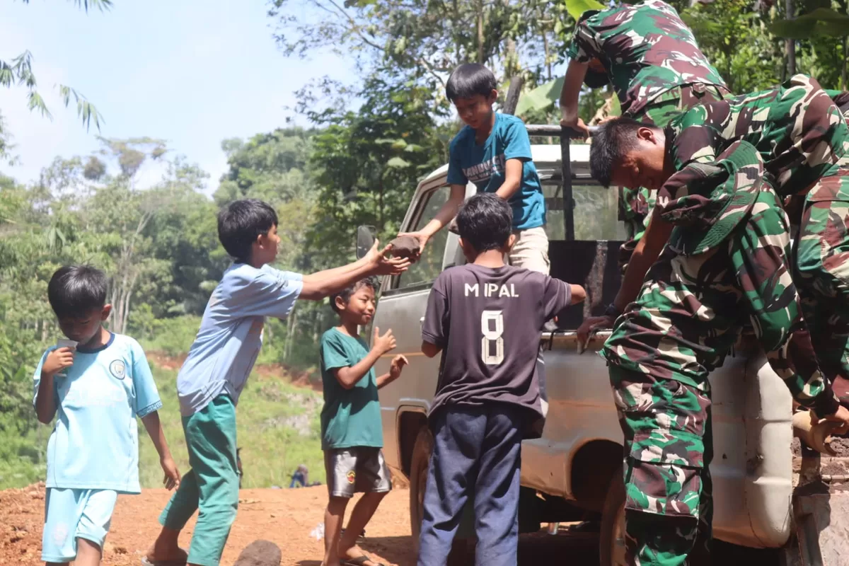 Sejumlah anak sekolah dari Desa Cikadongdong  bergotong royong membantu  memperkuat dan memadatkan struktur jalan desa. (Dok. TMMD Kodim0611/Garut)