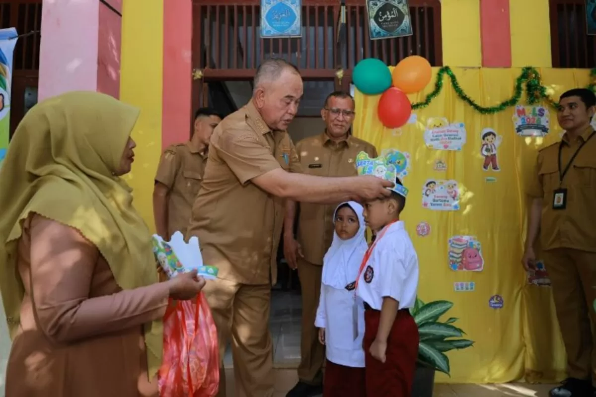 Camat Blang Bintang, Subhan SE MM turun mengalungkan tanda pengenal kepada siswa baru saat melakukan Monev MPLS di SDN Blang Bintang, Kecamatan Blang Bintang, Senin (13/7/2026).  (Dok. MC Aceh Besar)