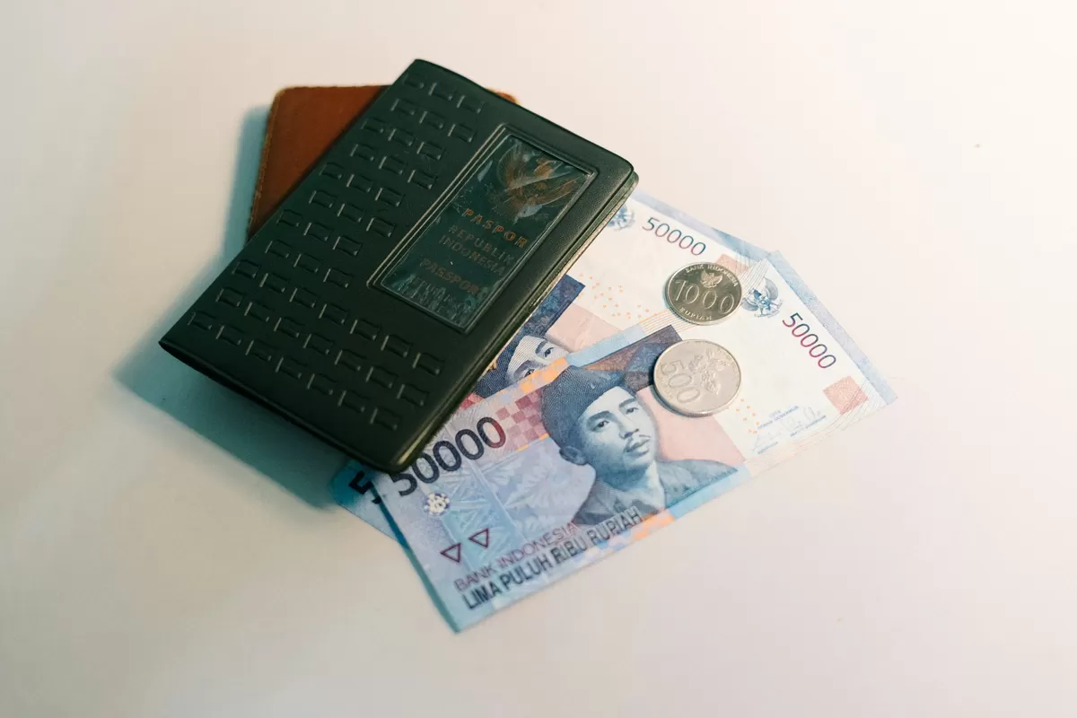 Paspor Indonesia bersama uang kertas dan koin rupiah. Ilustrasi penguatan nilai tukar rupiah terhadap dolar AS seiring pelemahan Indeks Dolar (DXY) pada Agustus 2026. (Foto: Unsplash/Bady Abbas)