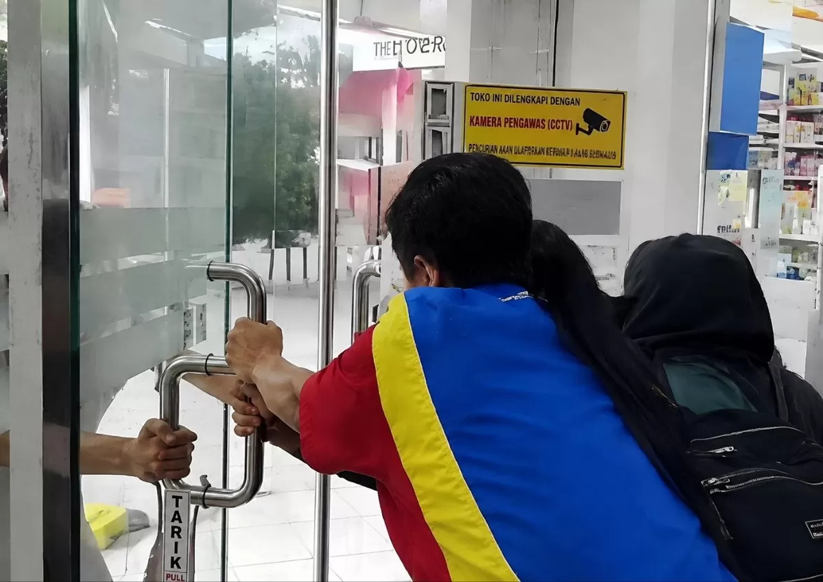 Seorang pria berusaha masuk ke minimarket di wilayah Poso, Pegawai menahan pintu dari dalam hingga terjadi aksi tarik-menarik.  (facebook:/amelhya mucsin)