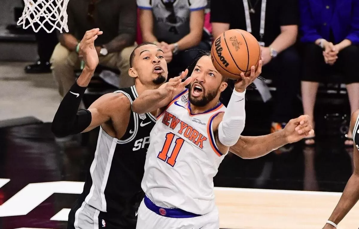 Bintang New York Knicks, Jalen Brunson berebut bola dengan pemain andalan Spurs Victor Wembayama dalam Gim 1 Final NBA 2026. Knicks sementara unggul 1-0 usai menang 105-95.