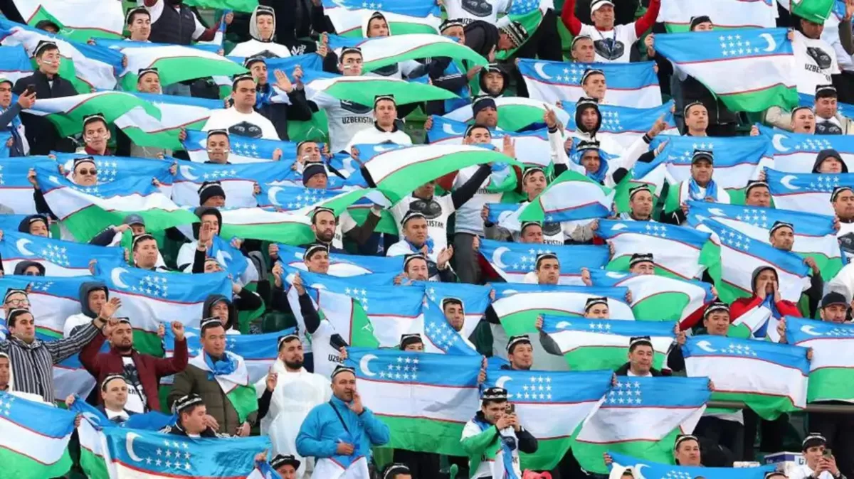 Para suporter Timnas Uzbekistan mengibarkan bendera negara mereka.
