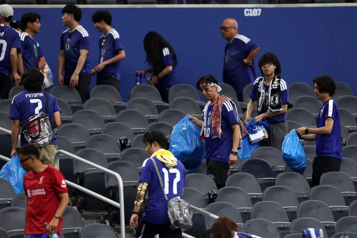Suporter Jepang membersihkan sampah di stadion pasca pertandingan melawan Belanda. 