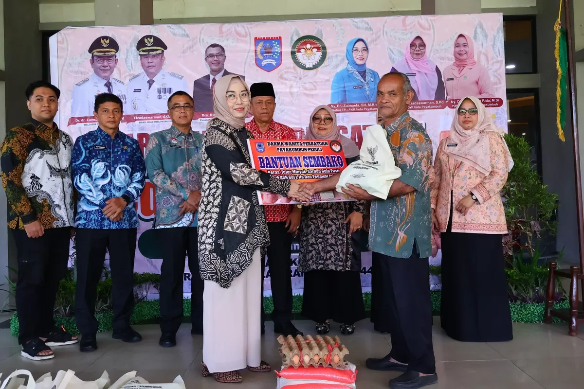 Ketua Dharma Wanita Persatuan (DWP) Kota Payakumbuh, Ny. Chece Rida Ananda, menyerahkan secara simbolis paket bantuan sembako kepada salah satu penerima dalam program DWP Berbagi dan Peduli di Lobi Balai Kota Payakumbuh, Kamis (12/03/2026).