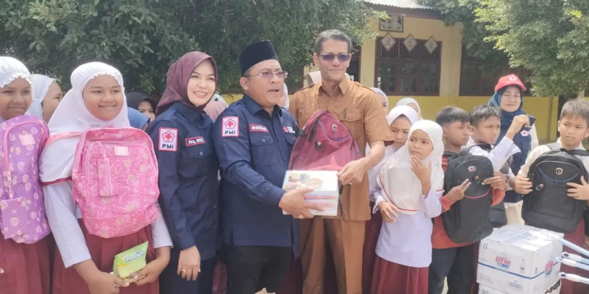 Ketua PMI Bireuen, Edi Saputra didampingi istrinya diabadikan bersama kepada kepala dan sejumlah murid SDN 7 Peusangan Selatan. Foto: AJ