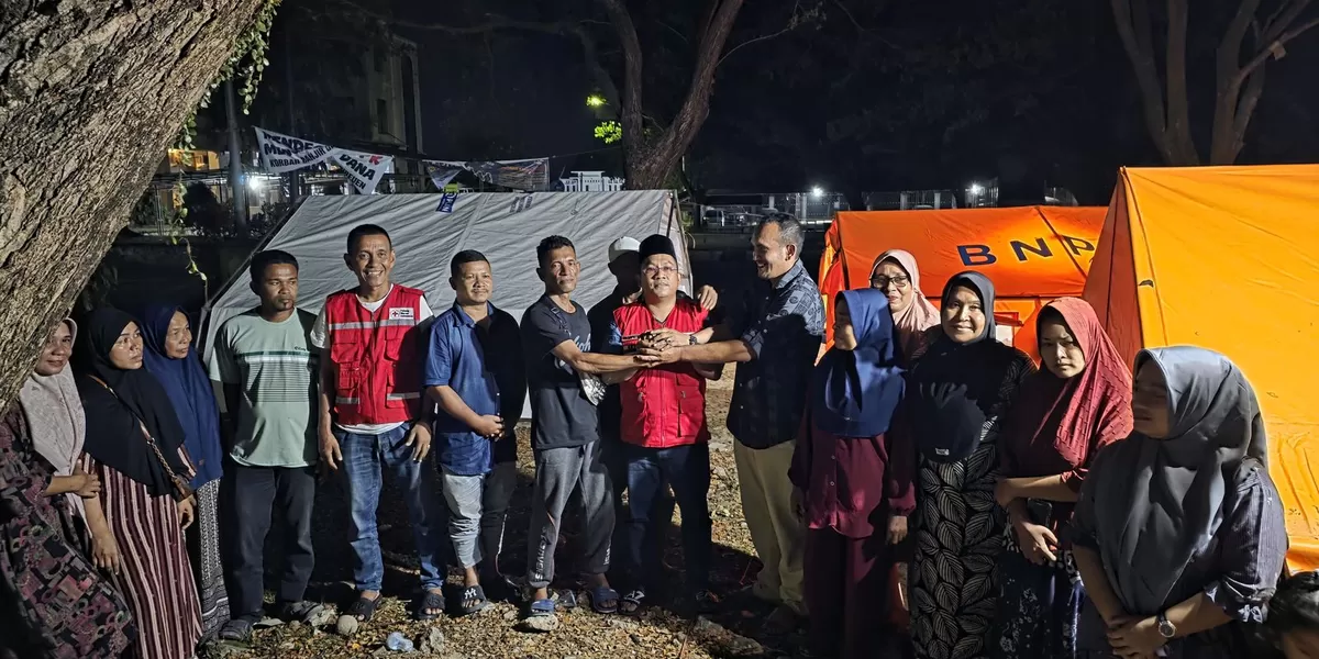 Ketua PMI Bireuen Edi Saputra (di tengah baju merah) bersama penyintas banjir sebelum membongkar tenda pengungsian di area kantor Bupati Bireuen. Foto: Dokumen Realitasonline. id
