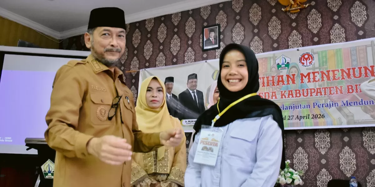 Wabup Bireuen, Razuardi (kiri) diabadikan setelah  memasang tanda peserta kepada seorang peserta pelatihan menenun. (AJ)