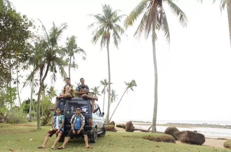 Spot foto keren di destinasi wisata alam Pantai Takisung Banjarmasin salah satunya adalah di bawah pepohonan kelapa background bibir pantai.