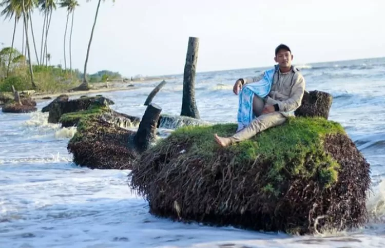 Spot foto keren di destinasi wisata alam Pantai Takisung Banjarmasin salah satunya adalah di bekas akar pohon kelapa.