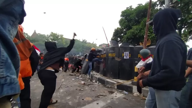 Pengunjuk rasa menendang barikade polisi saat demo ribuan pengemudi ojol di depan Mako Brimob Batalyon C Pelopor Solo, Jumat (29/8/2025). (SMSolo/Yoma Times Suryadi)