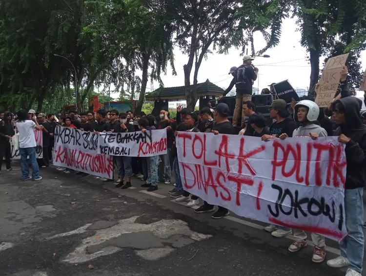 Massa pengunjukrasa memajangkan poster bertuliskan toal politik dinasti Jokowi di DPRD Sumut