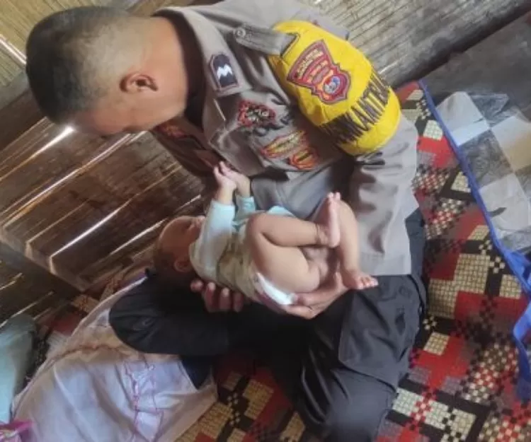 Aipda Sukiman saat menggendong Balita Stevano Yota penderita Atresia Ani di Desa Legur Lai, Elar