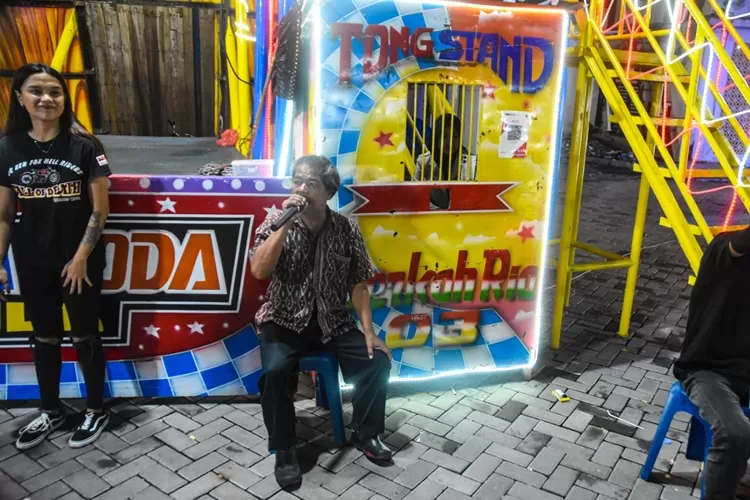 Rustam, pengelola Tong Setan Berkah Ria saat memanggil-manggil para pengunjung Pasar Malam untuk datang dan menyaksikan pertunjukan Karmila Purba. 