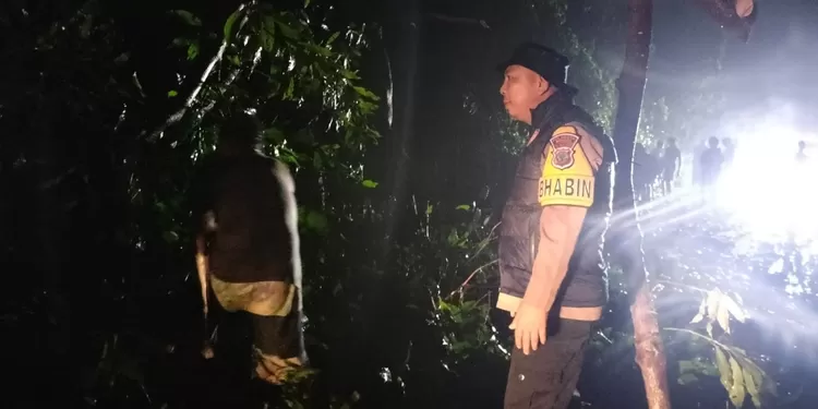 Bhabinkamtibmas Aipda Hendra Lempas saat berada di lokasi pohon tumbang Jalan Trans Tanawangko-Manado, Sabtu (14/2/2026). Kehadirannya memastikan koordinasi evakuasi berjalan cepat sesuai instruksi Kapolsek Pineleng.