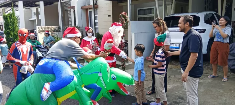 Seorang pria berkostum Santa Claus saat membagikan hadiah natal kepada umat Kristiani di Bellacasa Residence, Kelurahan Depok, Kecamatan Pancoranmas, Sabtu (6/12).