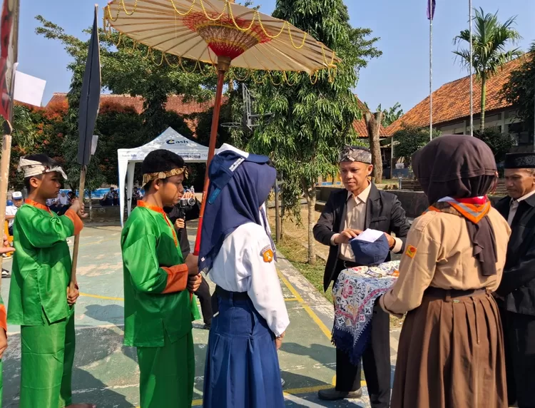 Kepala SMP Negeri 1 Serangpanjang, Tatang Rohana, melakukan simbolisasi pelepasan atribut siswa kelas 9 sebagai tanda resmi berakhirnya masa belajar di jenjang SMP dan awal perjalanan baru ke jenjang berikutnya