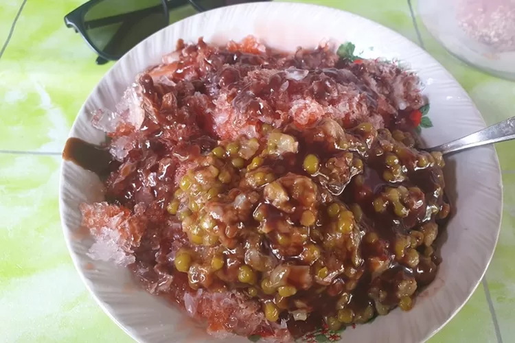 Saudah saat menyajikan bubur kacang hijau Pak Wawi di Kawasan Layur. (Ayosemarang.com/ Audrian Firhannusa)