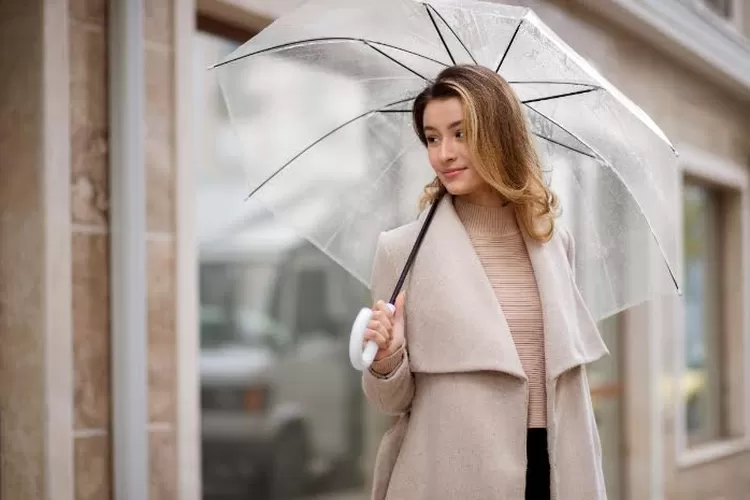 Ilustrasi perempuan menggunakan fashion musim hujan (Freepik)