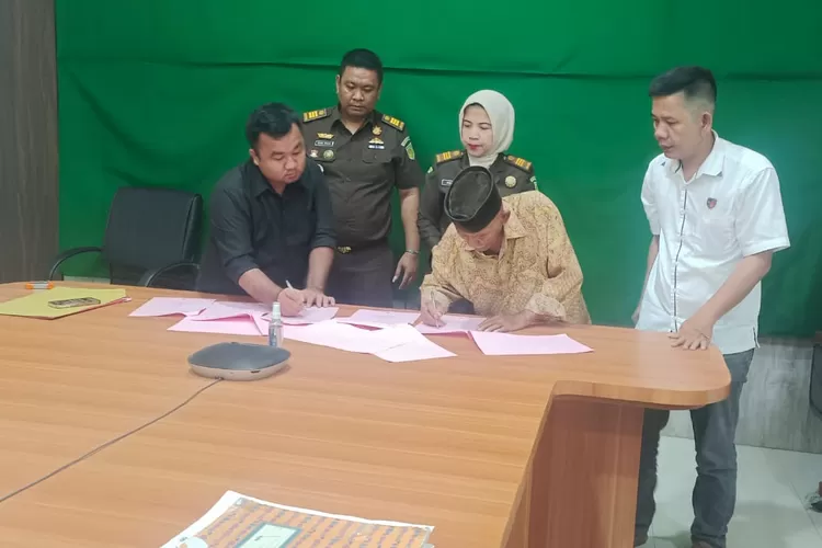 Terlapor menanda tangani berkas penyerahan dirinya di kantor Kejaksaan Negeri Lubuk Pakam (Realitasonline.id/zul)