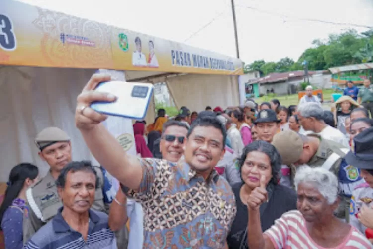 Walikota Medan Bobby Nasution saat selfie dengan warga yang memadati pembukaan pasar murah di Medan. (Realitasonline.id/Dokumen)