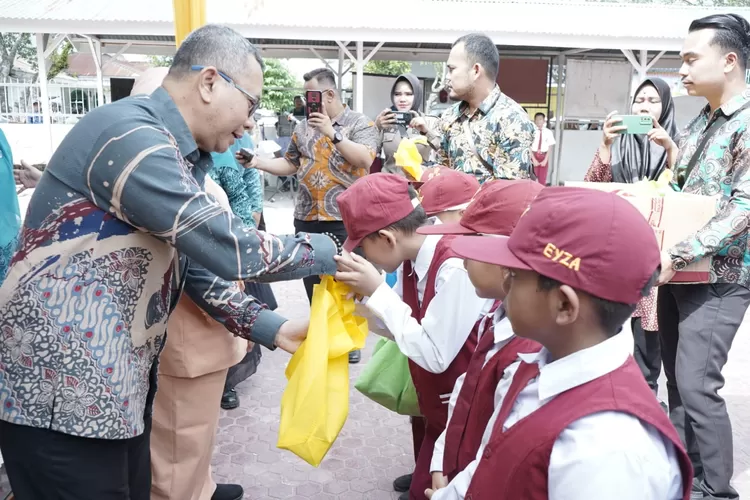 Kepala Dinas Ketahanan Pangan H. Ali Mughofar saat bersama Siswa SD yang menerima makan tambahan, di SDN 010086 Selawan, Kamis, (14/12/2023).   (Realitasonline.id/HS)
