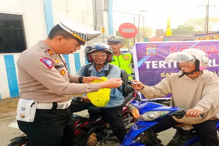 Kasat lantas Polres Batu Bara AKP H.W Siahaan membagikan souvenir berisi imbauan Tertib lalulintas (Realitasonline.id/Gusti)