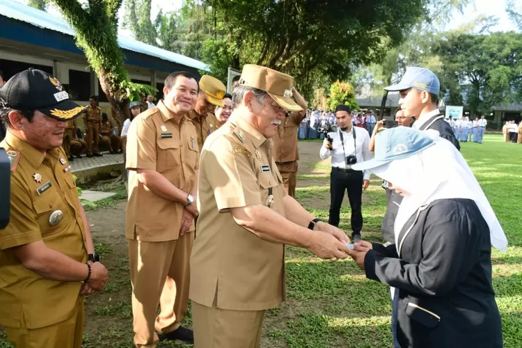 Kadisdukcapil Deli Serdang Misran Sihaloho (tidak pakai topi) mendampingi Bupati menyerahkan KTP kepada pelajar SMAN I Bangun Purba (Realitasonline.id/zul)