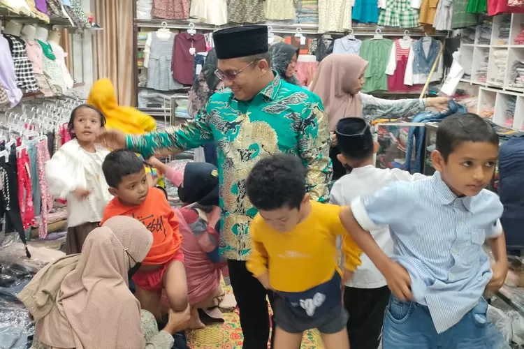 Edi Obama (pakai peci) bersama istrinya (jongkok) saat menemani anak yatim memilih baju lebaran di toko pakaian, kawasan Lapangan VOA Bireuen.