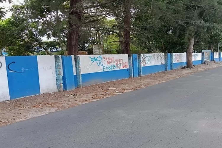 Terlihat pagar tembok SMPN I Pantai Labu dicoret-coret menggunakan cat pilox diduga dilakukan OTK saat libur sekolah R (ealitasonline.id/zul)