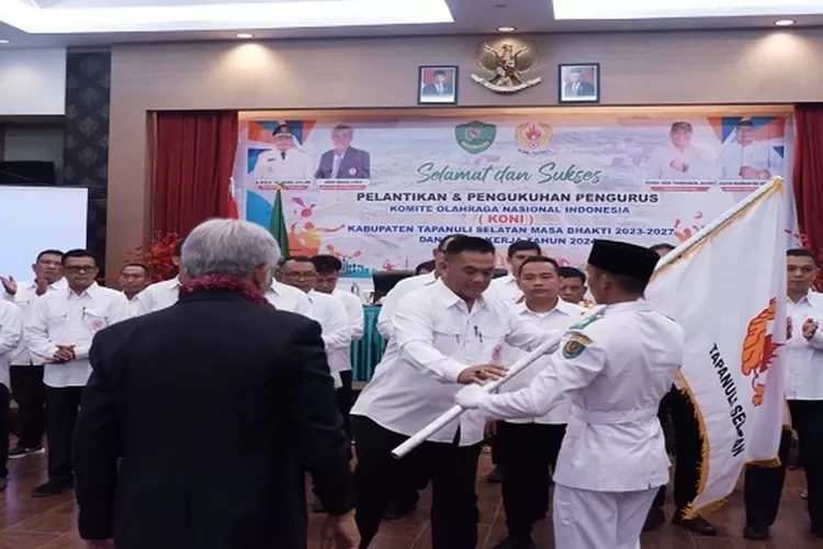 Ketua KONI Sumut Jhon Ismadi Lubis, menyerahkan pataka KONI kepada Kerua KONI Tapsel terpilih Haris Yani Tambunan pada pelantikan pengurus KONI Kabupaten Tapsel periode 2023-2027, ( Realitasonline.id/Riswandy)