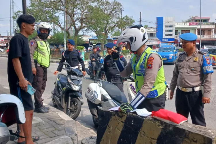 Polisi menilang pengendara sepeda motor yang tidak pakai helm pada Ops Patuh Toba 2024 di Bawah Fly Over Amplas, Selasa (16/7/2024).